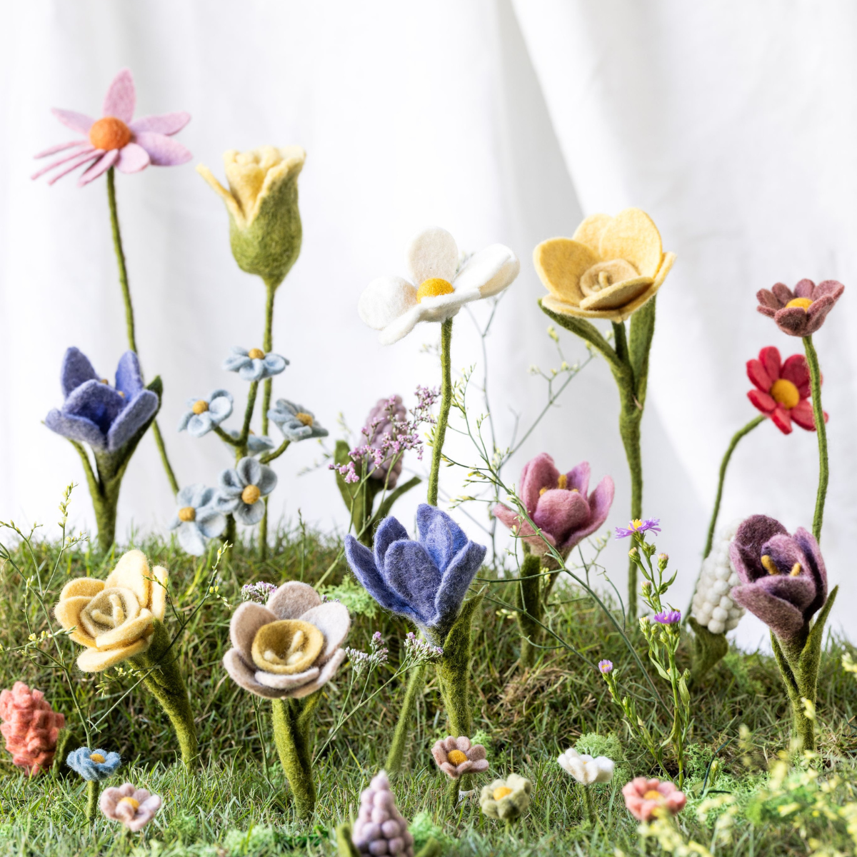 Gefilzte Osterfiguren und Blumen von Gry & Sif auf grünem Mooshintergrund.