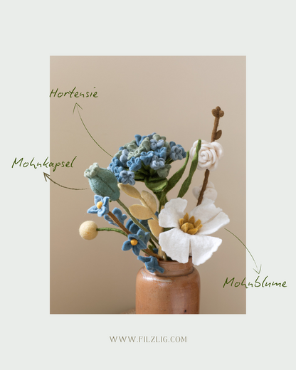 Blumenstrauß Pramila – Filzblumen für die Vase - Die Pramila-Komposition vereint klassische Formen mit einem verspielten Farbmix:

1x Hortensie in Blau

1x Mohnkapsel

1x Mohnblume

1x Rosenzweig

1x Blütenzweig mit zarten Blüten

2x Gräser für extra Volumen

1x Blattzweig in Buttergelb

1x Kugelblume